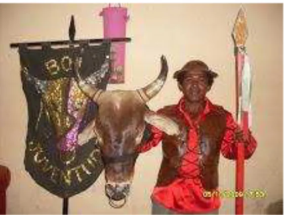 Figura  3  -  Zé  Ciro  segurando  a  cabeça  do  boi  e  sua  lança  de  vaqueiro,  com  o  primeiro  estandarte  do  Boi  Juventude ao lado direito da foto