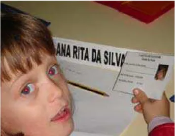 Foto 7 – Criança do Núcleo de Iniciação 1º ano,   prepara-se para votar, conferindo o seu Cartão de  Eleitora