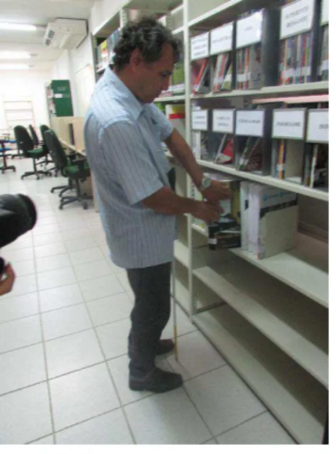 Foto 9 -  Voluntário “A “, folheando os livros de Braille na biblioteca. 