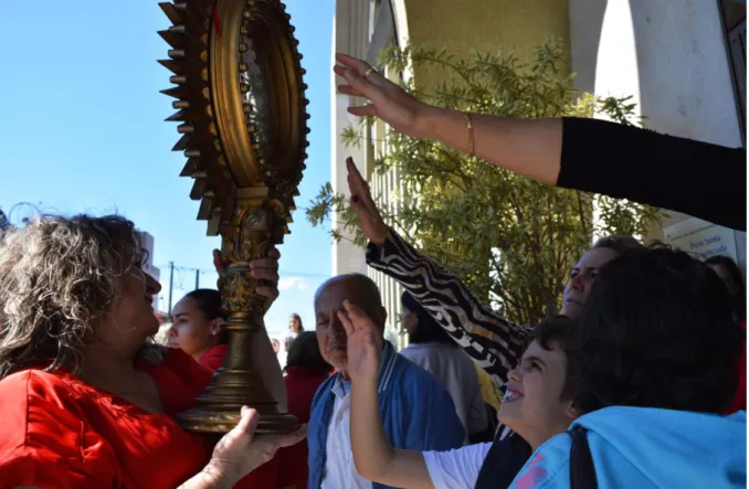 Figura 1: Ostensório com a imagem do Divino Espírito Santo sendo tocado por devotos de ambos os  sexos e diferentes faixas etárias em busca de bênçãos durante a Festa de Pentecostes, ocorrida em 