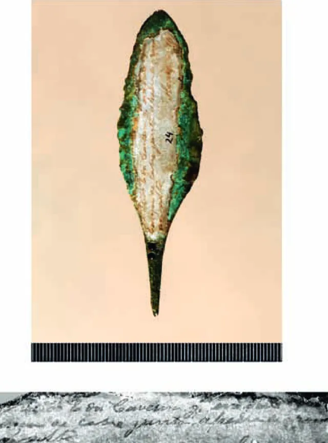 FIG. 0-5.   Etiqueta infelizmente totalmente aderente à ponta de projéctil de tipo Palmela, actualmente quase ilegível (reconhecem- (reconhecem-se, no entanto, as referências «a E[ste] da Caverna g[rande]» e «Lança de cobre junto a pedra…»