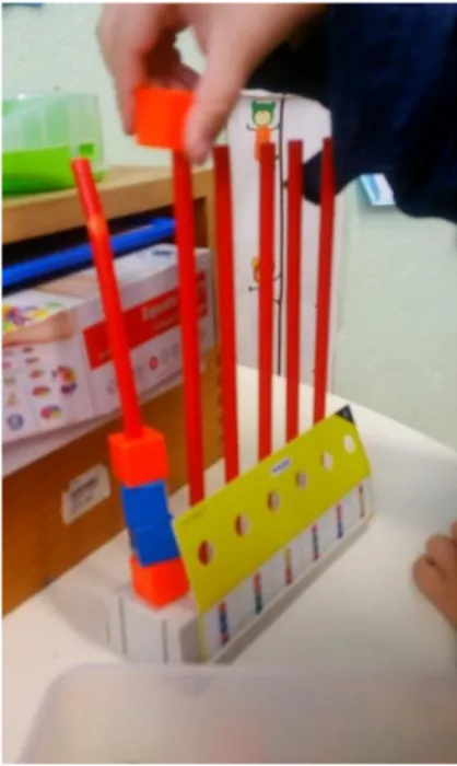 Figura 8 – Criança a colocar a peça  correta  da  sequência  de  cores  do  cartão (peça laranja).