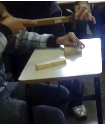 Figura 10  –  O professor posicionando a mão do aluno 3c paralelamente à mesa. 