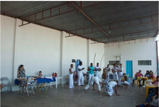 Foto 1: Apresentação da Capoeira de Pinhões no Chá com Quitanda.   No primeiro plano a farta mesa com chás, sucos e quitandas, e ao fundo uma mesa com exposição 