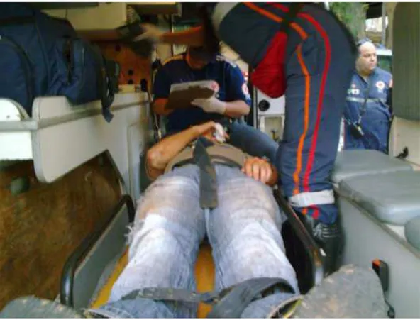 FIGURA  2  –  Dentro  da  ambulância,  paciente/usuário  deitado  na  „prancha‟,  enquanto  trabalhadores/técnicos  de  enfermagem,  nesse  momento,  verificam  sinais  vitais  e  um  deles  anota  dados  do  atendimento;  motorista  conversa  com  policia