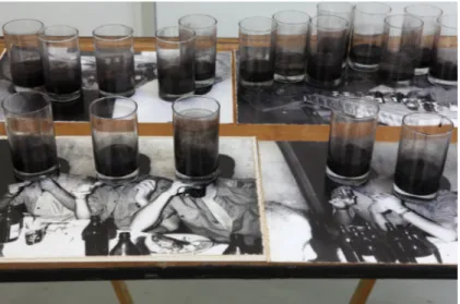 Figure 13: Daniel Barroca, Obstructed Images, 2011. Glasses with murky water on inkjet prints on  wooden table, 140 x 70 x 75 cm  