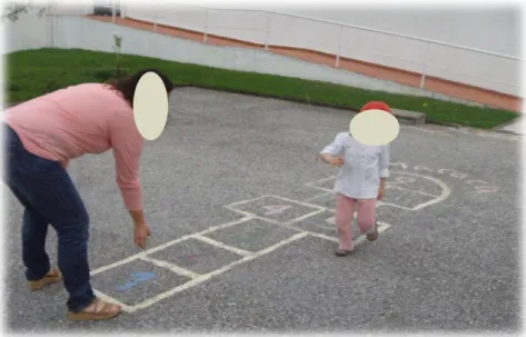 Fig. 2 – Comemoração do Dia da Mãe, espaço exterior: C. (4A) a  explorar o jogo do stop no chão, com a sua mãe