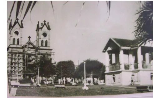 Foto  1  -  Vista  do  jardim  do  coreto  e  a  matriz  Nossa  Senhora  do  Carmo,  em  construção  na  década de 1960, em Frutal - MG 