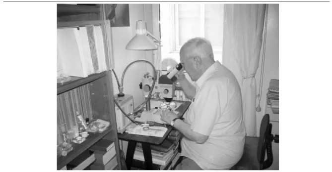 Fig. 6. Joaquim Mateu, l’any 2005, assegut davant la lupa binocular al laboratori que va instal·lar al seu  pis del carrer Còrsega