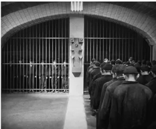 Figura 3: Cena do filme Metrópolis (1927), de Fritz Lang. Os operários adentram  a fábrica como se adentrassem uma prisão, além de caminharem como robôs, 