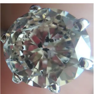 Figura 12. Três inclusões de grafita no centro de um  diamante foram duplicadas pelas facetas por toda  a gema