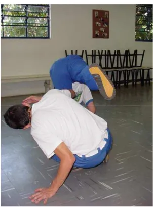 Figura 14 - A chapa de costas é dada estando com o tronco flexionado à frente com ambas as mãos apoiadas no  chão (com os braços estendidos) de modo que olhe por baixo das pernas