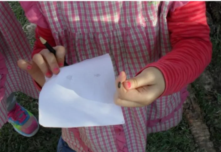 Figura 4. 11: Criança com o registo (através do desenho) e o bicho-de-conta encontrado no quintal
