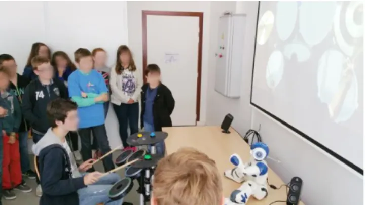 Figure 3- Photo of a class of 12 y-o children discovering the  virtual drum teacher (faces blurred for anonymity)