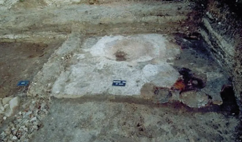 Fig. 120 – Le sol de l’habitat en « D ». On note les couches de craie sur  un sol de terre battue, la sole en argile indurée et noircie au centre de la  pièce ; au premier plan, en plus sombre, les fours arasés et, en noir, les  couches de cendres et charb