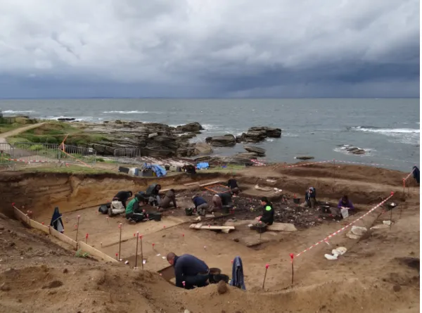 Fig. 7 – Vue du site en cours de fouille en 2014, depuis le nord-est. La différence est nette entre le niveau coquillier de couleur  sombre et sa périphérie de couleur brun clair (cliché G