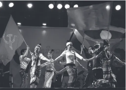 Fig. 9 : Danse d’ouverture d’un festival représentant des femmes en costume  ethnique dansant sous les drapeaux communistes et laotiens