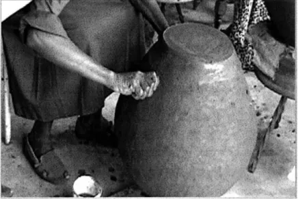 Figure 7-2:  Amilo-Rangwe  potter tapping  a clay  vessel.  Potter uses  1&#34;  diameter PVC  tubing to  create initial opening.