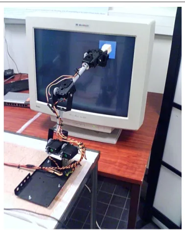 FIGURE 1 | Lynxmotion SES robotic arm in front of a touch screen used for Experiment 1.The screen is perceived by a webcam