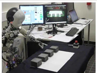 FIGURE 3 | iCub robot performing Experiment 3. The robot chooses among four cubes on a table
