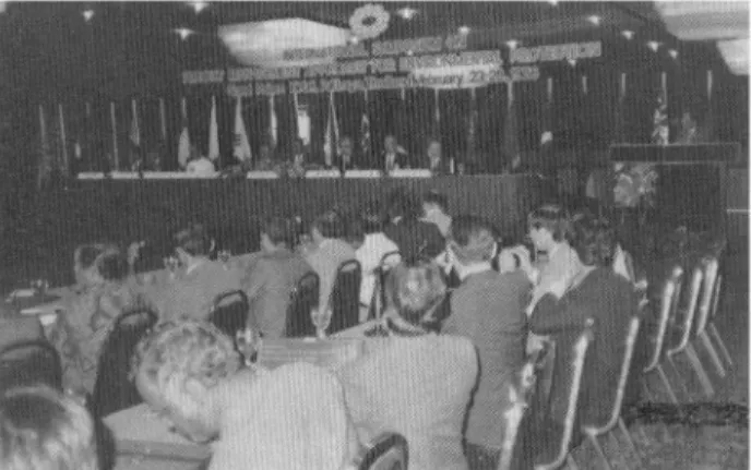 FIG. 1. Looking over a 'wing' of participants to the colourful, flag- flag-draped and flower-decked platform, with speaker on right.