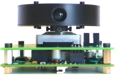 Figure 2.6: Picture of the sensor with the rotating turret in black (top) and the lens, the stepper motor (middle), the optical switch (middle right), and the electronic card (bottom).