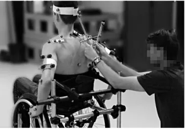 Figure 1: Photograph of a trained experimenter maintaining  the  scapula  locator  on  the  scapula  while  the  subject  is  propelling on the MWC simulator