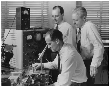 Figure 1.17: John Bardeen(with spectacles), William Shockley (using the microscope) and                                             Walter Brattain (standing behind) at Bell Labs, 1948  [43] 
