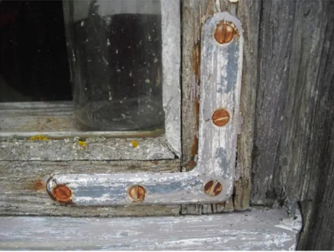 Figur 4. Ett fönster från en av byggnaderna i Kovik med spår av målarfärg i grått samt rostiga skruvar vilket  indikerar att byggnaden är äldre