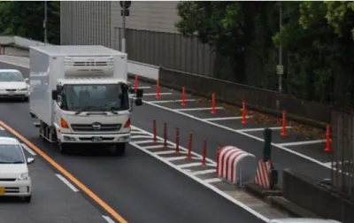 Figur 3  Större väg i Tokyo där man använder sig av olika färger som vägmarkeringar  men även tvärgående markeringszoner och koner för att begränsa körfält och för att  reducera hastigheterna