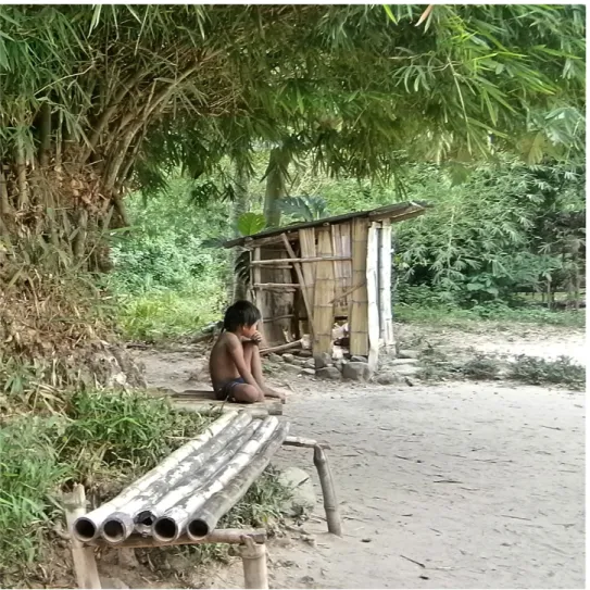 Figur	
  2.	
  En	
  Mangyanpojke	
  sitter	
  under	
  ett	
  bambuträd	
  i	
  sin	
  hemby.	
  (Fotograf,	
  Kristina	
  Söderling,	
   2012-­‐04-­‐20).	
  