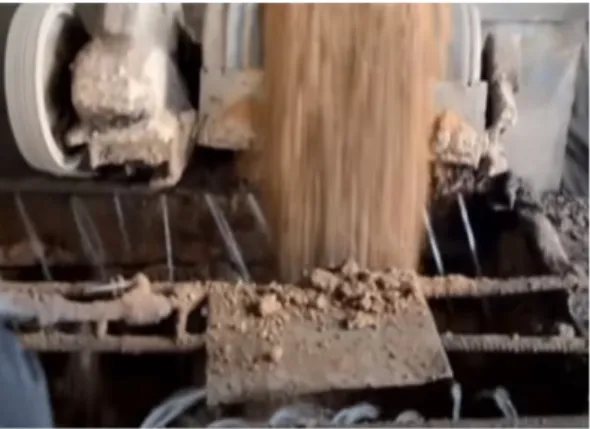 Figure 11: Factory worker shovelling coal into clay mixture on conveyor belt.
