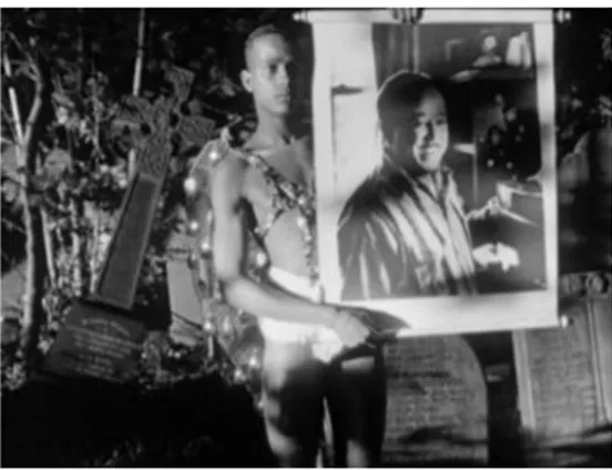 Figure 1.4  Screenshot. A young African-American man wearing an angel costume in a cemetery  shows Langston Hughes‘ poster to the camera